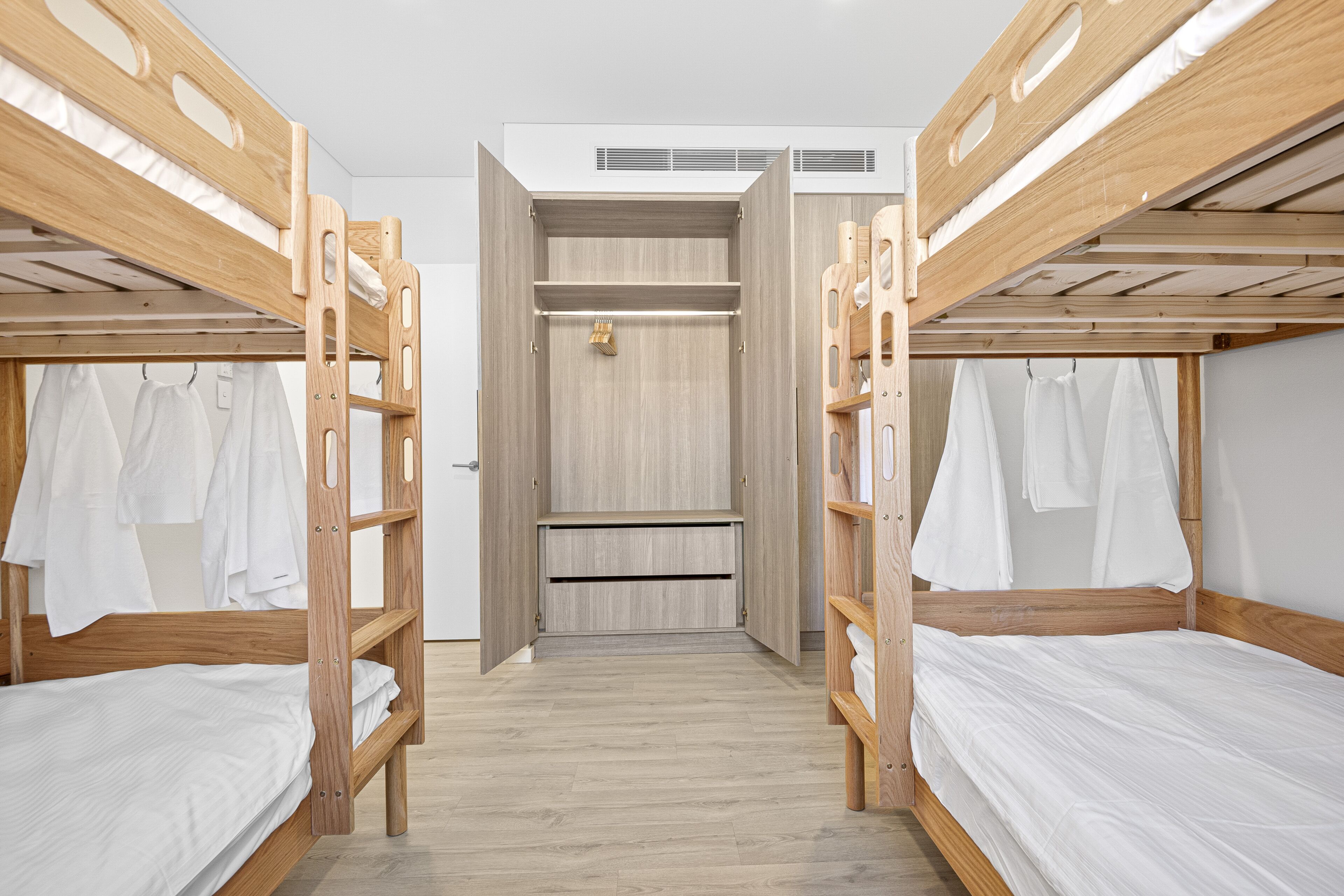 Ein Zimmer mit Etagenbetten, einem Kleiderschrank und einer Dusche.