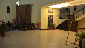 A spacious lobby with a staircase, seating area, and potted plants. - Hotel Grand Riviera (Paonta Sahib)