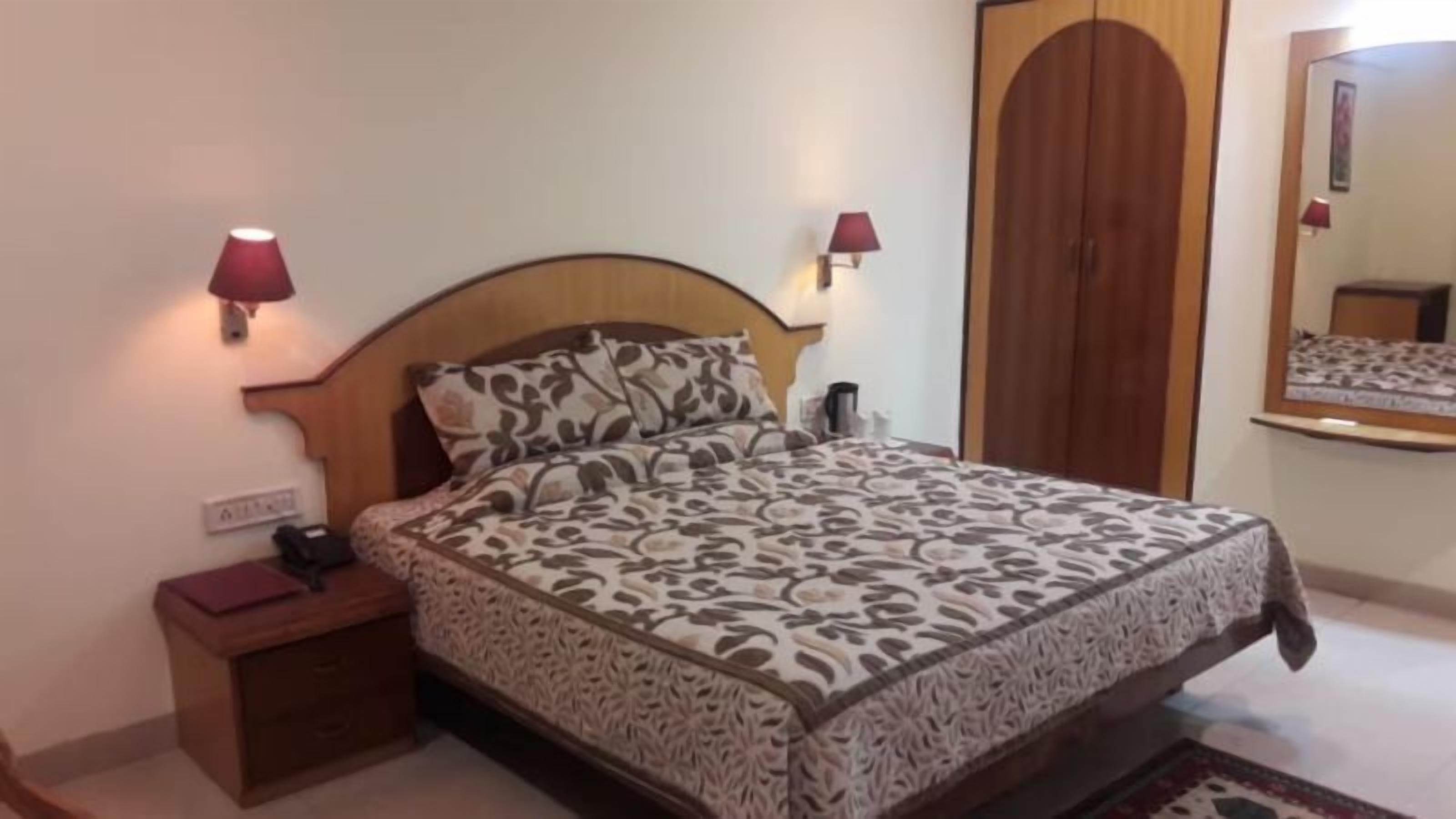 A bedroom with a bed, nightstands, a wardrobe, and a mirror.