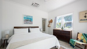 Un dormitorio con una cama grande, un tocador, una silla y una ventana con cortinas.