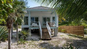 Una casa de playa con terraza de madera, una escalera y vistas al océano.