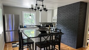 Une cuisine moderne dotée d’un îlot central, de planchers en bois et d’un mur d’accent en briques noires.