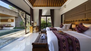 A modern hotel room with a large bed, a smaller bed, a bench, a desk, and a view of a pool and greenery.