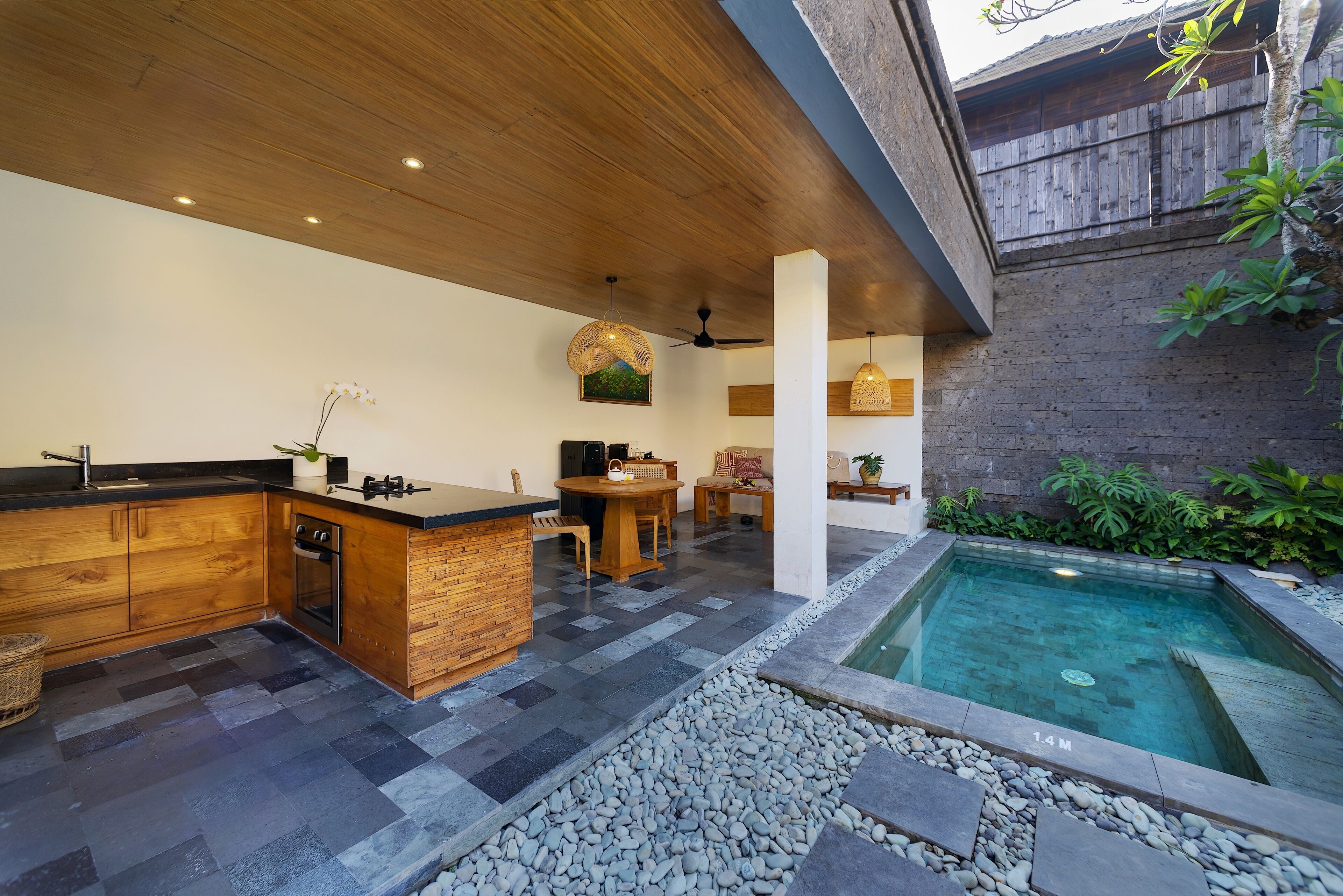 A modern kitchen with a wooden countertop, a built-in oven, and a dining area with a round table and chairs.