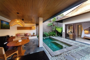 A modern outdoor living space with a pool, seating area, and a dining table.