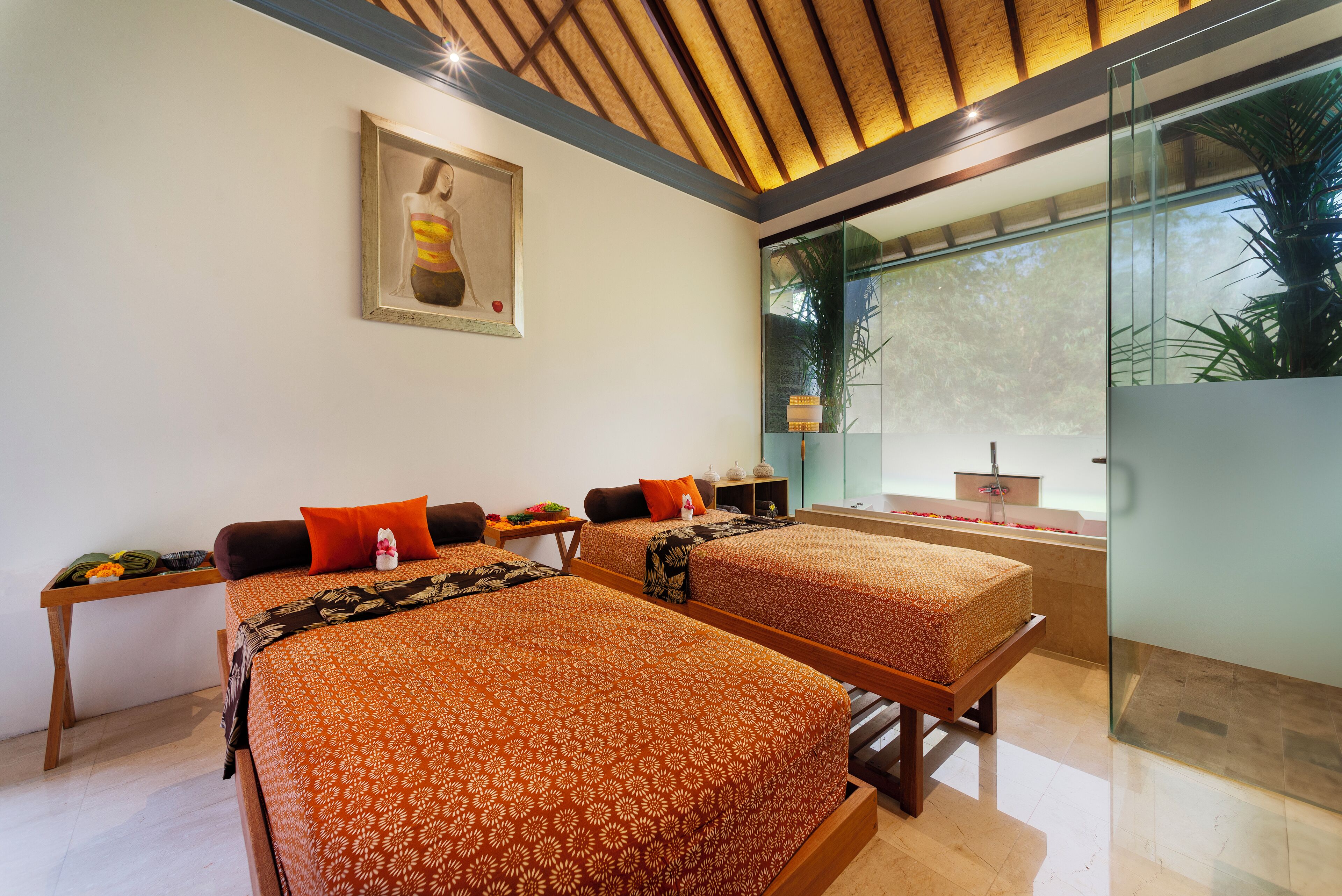 Habitación de hotel moderna con dos camas, un ventanal con vistas a zonas verdes, un cuadro en la pared y una mesita con artículos de cortesía.