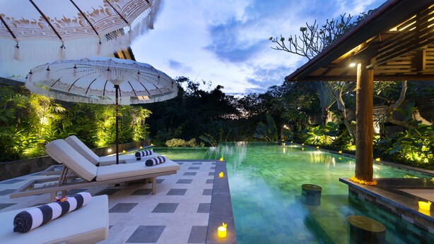 A serene outdoor pool area with lounge chairs and a pergola.