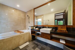 Un baño moderno con un espejo grande, una bañera, un lavabo y un mueble de tocador con un armario de madera.
