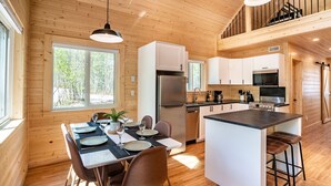 Una cucina moderna con pareti in legno, un'isola centrale e un'area pranzo con tavolo apparecchiato per quattro.