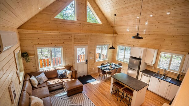 Un accogliente chalet con camera da letto soppalcata, zona pranzo e cucina.