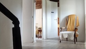 Una habitación amplia con techo de madera, una puerta blanca y una silla cubierta con tela amarilla.