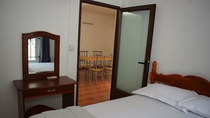 A bedroom with a wooden bed, a bedside table with a mirror, and a chair. - Seafront Apartment Villa (Flic en Flac)