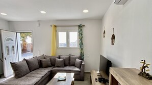Una sala moderna con un sofá modular, una mesa de centro de madera y un mueble para televisión.