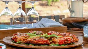A wooden table with a plate of food, glasses, and a pitcher. - Koro River Camp  (Tuli Lodge)