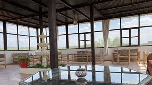 A spacious room with large windows, wooden furniture, and a central glass table with decorative items. - Oloft (Marrakech)