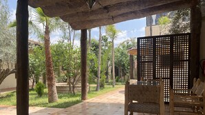 A covered patio area with tiled flooring, a table with chairs, and a decorative screen. - Oloft (Marrakech)