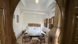 A room with a bed, a wooden table, and a patterned floor. - Oloft (Marrakech)