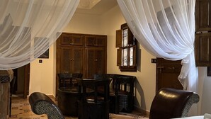 A room with a bed, a dining table with chairs, and a window with curtains. - Oloft (Marrakech)