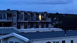 A row of townhouses with a flat roof, a visible garage, and a small balcony on the second floor. - Sea-side holiday home with balcony views to the sea (Hunstanton)