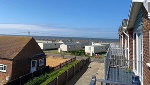 A residential area with houses, a clear sky, and a view of the sea. - Sea-side holiday home with balcony views to the sea (Hunstanton)