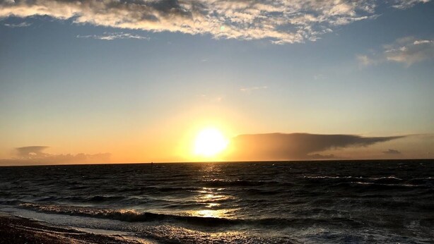 A sunset over the ocean with a clear sky and calm waters. - Sea-side holiday home with balcony views to the sea (Hunstanton)
