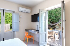A room with a bed, a desk with a chair, a TV, and a balcony with a table and chairs. - Vico San Lorenzo - Camere a Salina (Malfa)