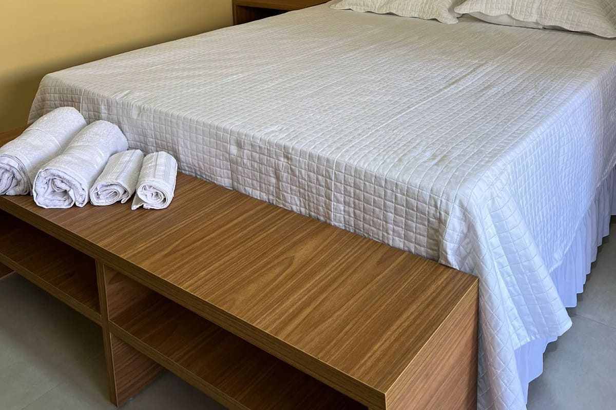 Una cama bien tendida con un cabecero de madera y un banco a juego al lado.