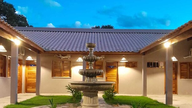A courtyard with a central fountain, surrounded by a covered walkway and wooden doors. - Hotel do Carmo (Piracuruca)