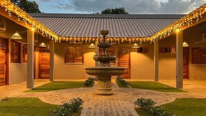 A courtyard with a central fountain, surrounded by a building with multiple rooms and a tiled roof. - Hotel do Carmo (Piracuruca)