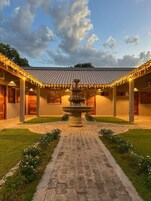Un patio central con una fuente, rodeado por un edificio con varias habitaciones y un techo de tejas.