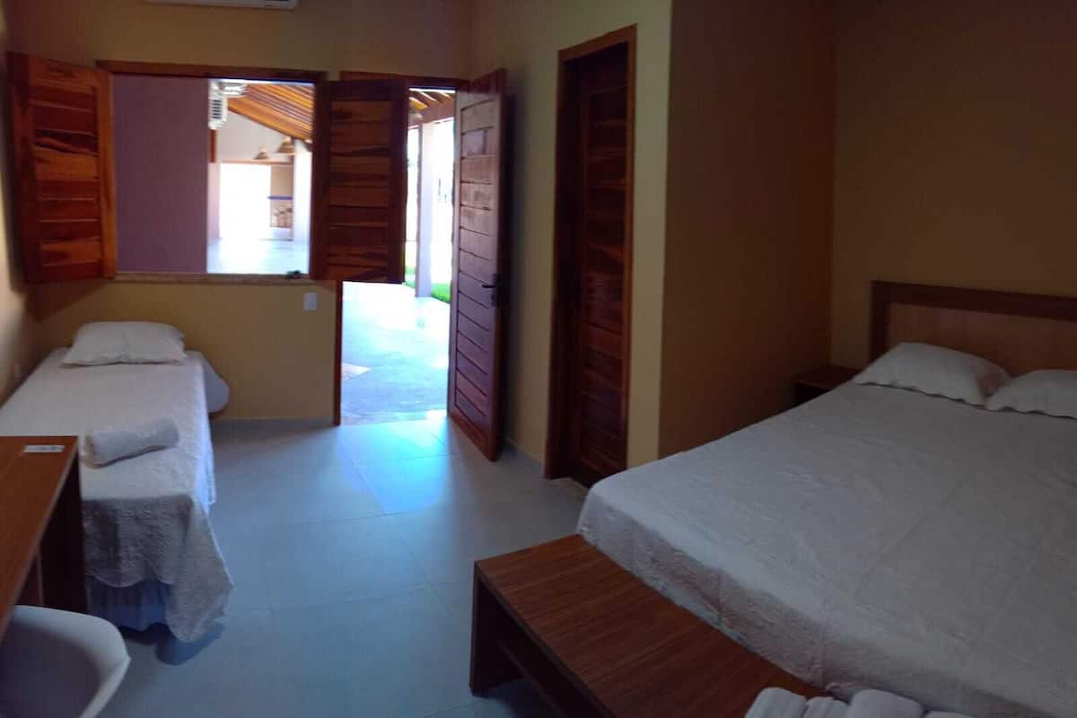 Una habitación con dos camas, un banco de madera y una mesita.