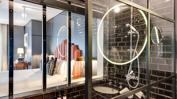 Een moderne badkamer met een glazen douchecabine, een ronde spiegel en een open douche.