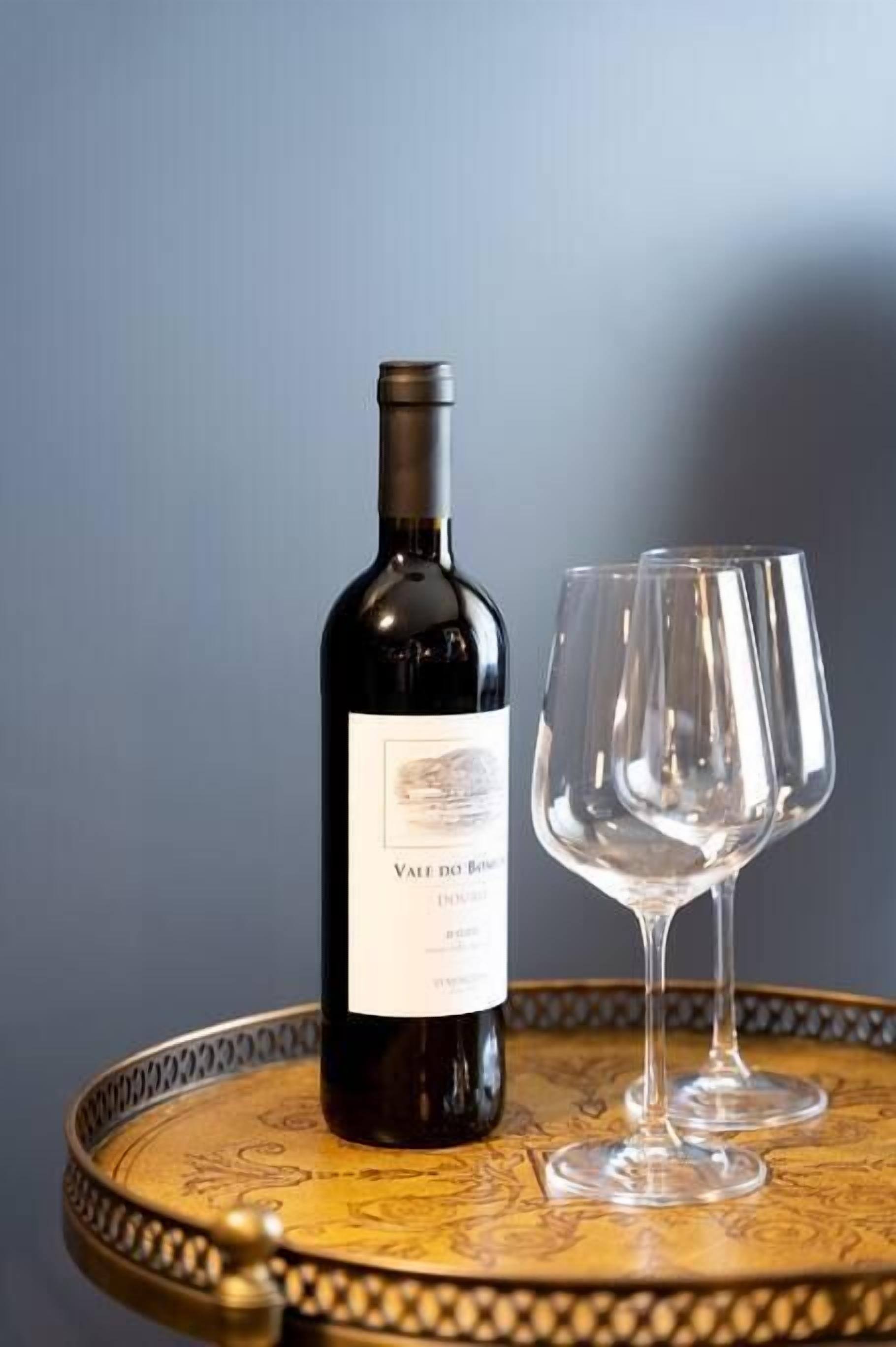 A bottle of wine on a round table with a decorative edge.