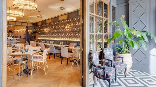 Un restaurant moderne doté d’un plancher en bois, de murs décorés de motifs variés et d’un choix de différents types de sièges, notamment des chaises et des tables.