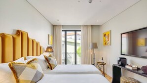 Une chambre d’hôtel avec deux lits, une télévision, un bureau et un balcon avec des rideaux.