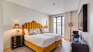 Une chambre d’hôtel moderne avec un lit double, une table de chevet, une commode, une télévision et une grande fenêtre avec des rideaux.