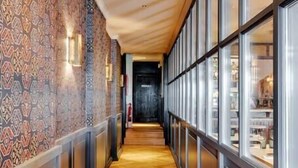 Un couloir avec un papier peint à motifs, un plancher en bois et de grandes fenêtres.