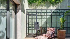 Un espacio exterior moderno con asientos estampados y una planta grande en maceta.