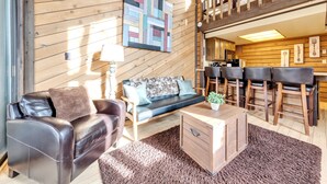 A cozy living room with a sofa, a coffee table, and a dining area with chairs. - Snowshoe Village 5A Ski In/Out Condo (Brian Head)