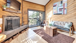 A cozy living room with a fireplace, a sofa, and a television mounted on the wall. - Snowshoe Village 5A Ski In/Out Condo (Brian Head)