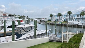 A marina with boats docked, a white fence, and a light blue building with stairs. - Charter Landing II unit C9 Luxury Waterfront Condo in Orange Beach.
 (Orange Beach)