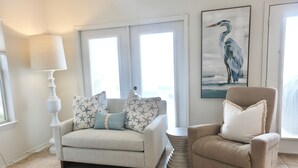 A living room with a beige sofa, a matching armchair, a round side table, and a painting of a bird on the wall. - Charter Landing II unit C9 Luxury Waterfront Condo in Orange Beach.
 (Orange Beach)