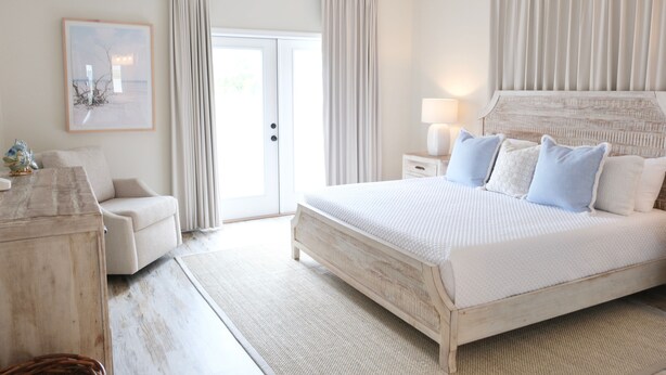 A bedroom with a large bed, a bedside table with a lamp, a chair, and a door leading to a balcony. - Charter Landing II unit C9 Luxury Waterfront Condo in Orange Beach.
 (Orange Beach)