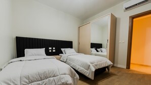A bedroom with two beds, a large mirror, and a wardrobe. - Luxury doublex apartments in new cairo
شقق فندقيه للايجار بالتجمع الخامس  (Cairo)