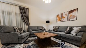 A modern living room with a sectional sofa, a wooden coffee table, and abstract wall art. - Luxury doublex apartments in new cairo
شقق فندقيه للايجار بالتجمع الخامس  (Cairo)
