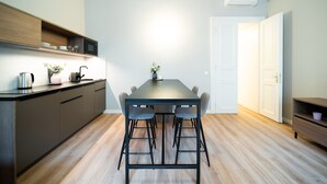 A modern kitchen with a dining table and chairs, wooden cabinets, and a microwave. - Karl BY ZEITRAUM (Prague)