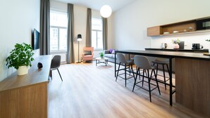 A modern kitchen with a wooden countertop, bar stools, and a large window with curtains. - Karl BY ZEITRAUM (Prague)