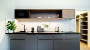 A modern kitchen with a built-in microwave, a coffee maker, and a potted plant. - Karl BY ZEITRAUM (Prague)
