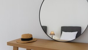 Un espejo redondo sobre una mesa de madera con un sombrero de paja a su lado.