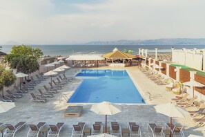 A pool area with lounge chairs and umbrellas, a covered seating area, and a view of the sea. - LA PLAYA GRANDE (Corfu)